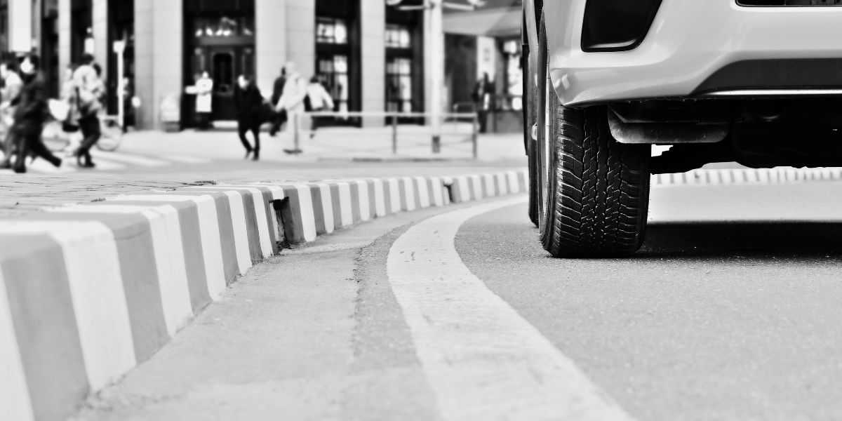 black and white close up of a vehicle at the curb, taken from street level